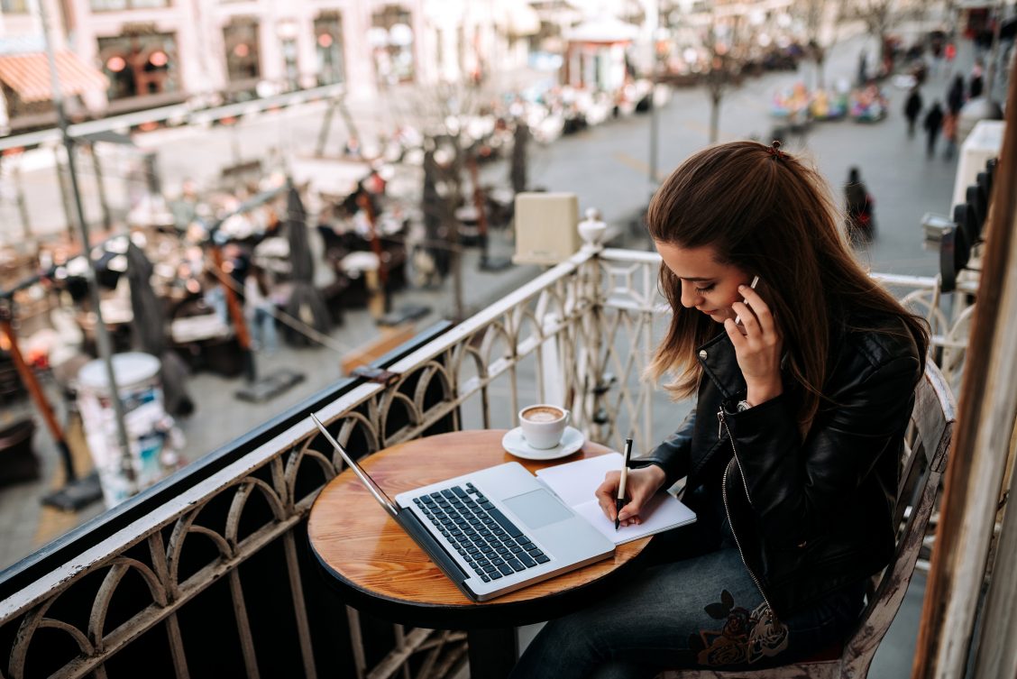 Man aan het werk op zijn laptop en is aan de telefoon.